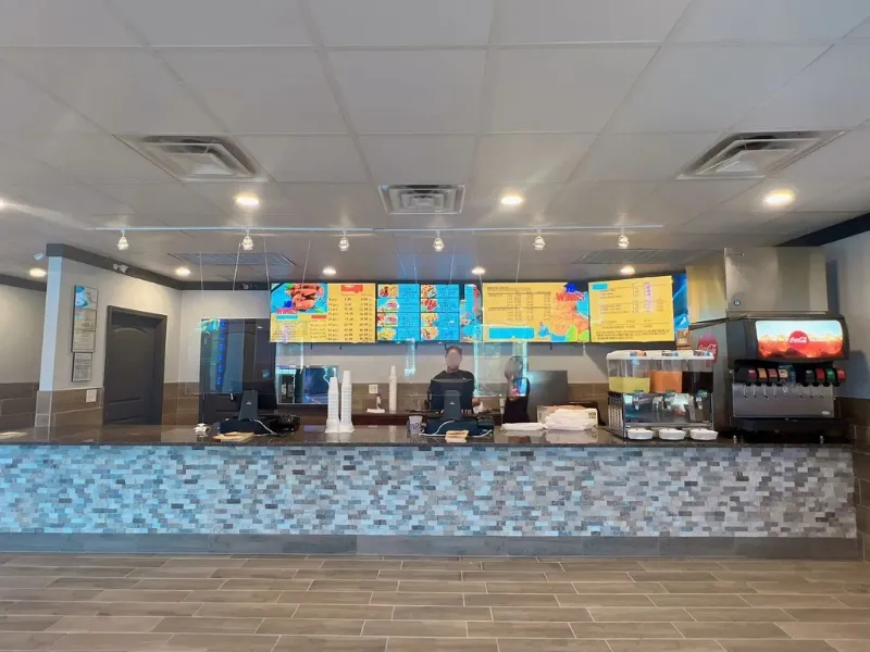 The service counter with menu boards and staff working at JD WINGS, an Fast food Restaurant in Columbus